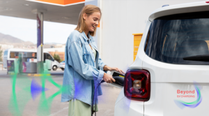 Woman charging an EV car at a station, illustrating the 5th edition of the Beyond EV Charging papers by Gireve